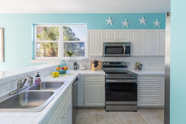 kitchen featuring sink, white cabinets, stainless steel appliances, and backsplash