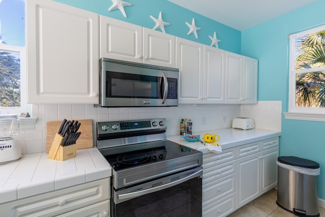 kitchen featuring white cabinets, stainless steel appliances, and a healthy amount of sunlight