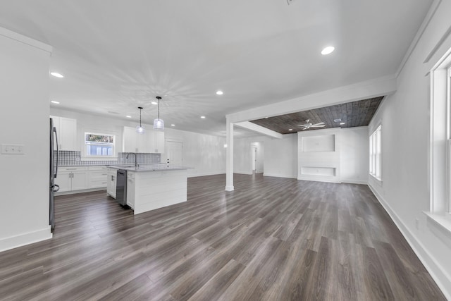 kitchen with appliances with stainless steel finishes, white cabinetry, hanging light fixtures, tasteful backsplash, and a center island with sink