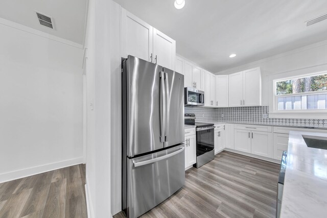 kitchen with backsplash, light hardwood / wood-style flooring, stainless steel appliances, and white cabinets