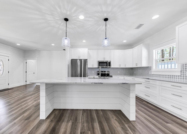 kitchen with an island with sink, white cabinetry, hanging light fixtures, stainless steel appliances, and light stone countertops