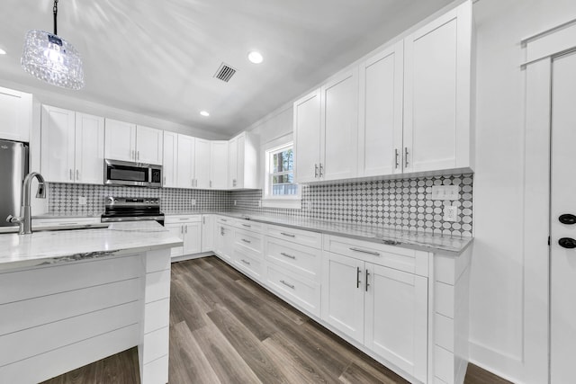 kitchen with appliances with stainless steel finishes, pendant lighting, tasteful backsplash, white cabinetry, and sink