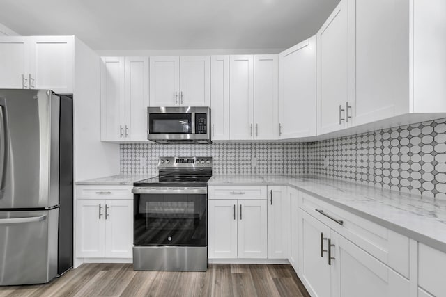 kitchen with white cabinetry, appliances with stainless steel finishes, light stone counters, and wood-type flooring