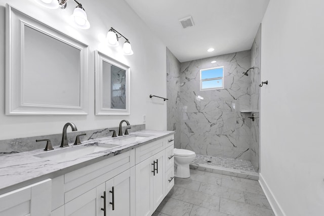 bathroom with vanity, toilet, and tiled shower