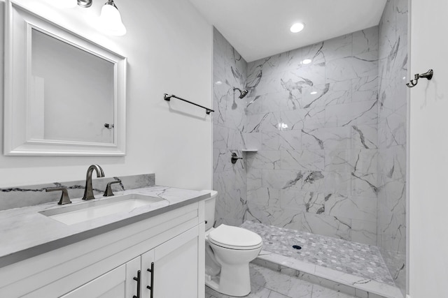 bathroom featuring vanity, a tile shower, and toilet