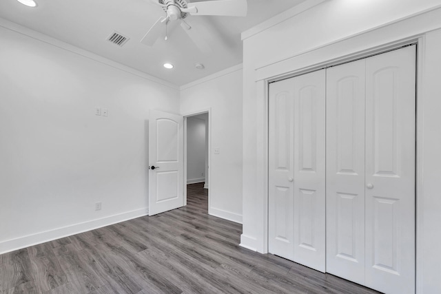 unfurnished bedroom featuring crown molding, ceiling fan, wood-type flooring, and a closet