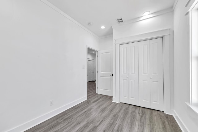 unfurnished bedroom with crown molding, light hardwood / wood-style floors, and a closet