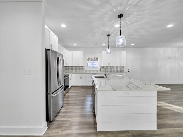 kitchen with a kitchen island with sink, white cabinetry, pendant lighting, and stainless steel appliances