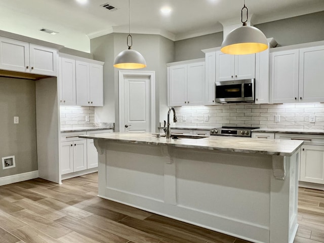 kitchen featuring white cabinetry, sink, hanging light fixtures, stainless steel appliances, and a center island with sink