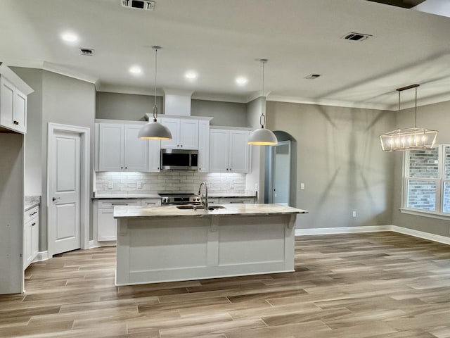 kitchen featuring white cabinetry, pendant lighting, tasteful backsplash, and a center island with sink