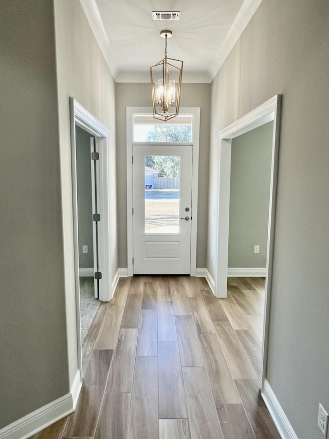 doorway with ornamental molding and a chandelier