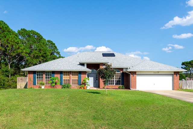 ranch-style home with a front yard, solar panels, and a garage