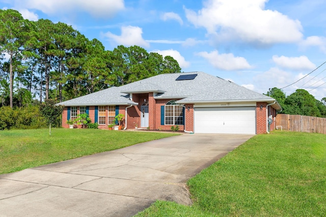 single story home with solar panels, a garage, and a front lawn