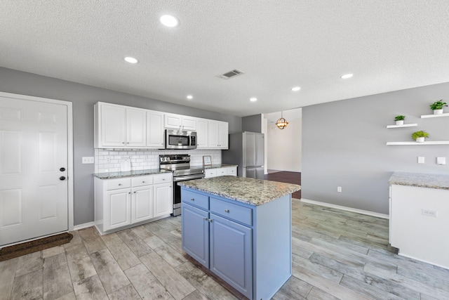 kitchen featuring stainless steel appliances, a kitchen island, backsplash, light hardwood / wood-style floors, and white cabinets