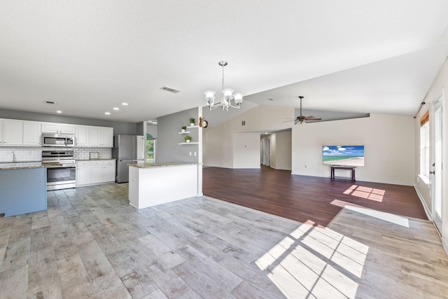 kitchen featuring white cabinets, appliances with stainless steel finishes, vaulted ceiling, and light hardwood / wood-style flooring