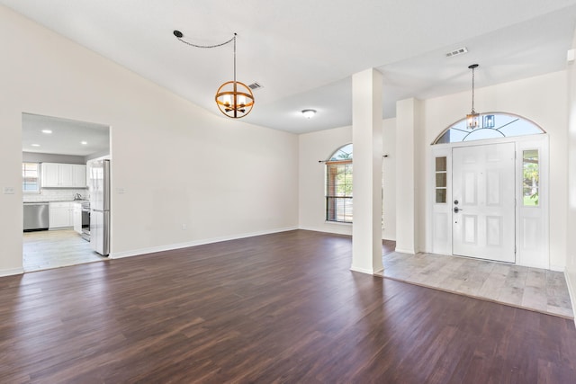 foyer with wood-type flooring, high vaulted ceiling, and a chandelier