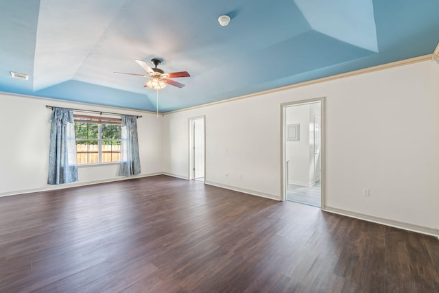 empty room with dark hardwood / wood-style flooring, a raised ceiling, and ceiling fan