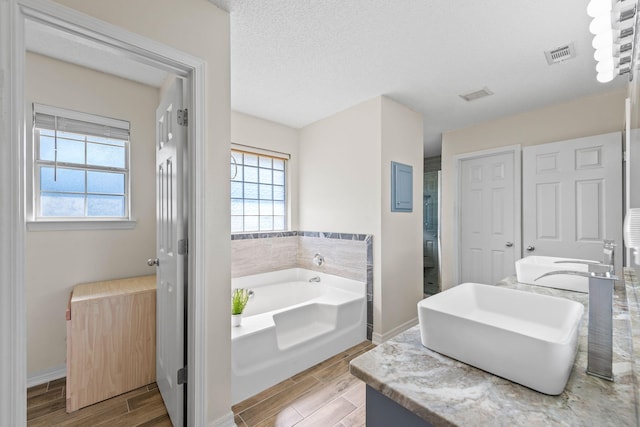 bathroom with a textured ceiling, vanity, hardwood / wood-style flooring, and shower with separate bathtub