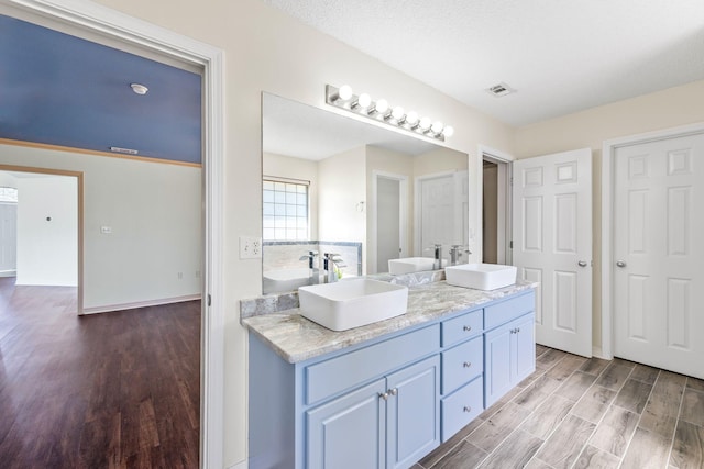 bathroom with vanity, hardwood / wood-style floors, and a textured ceiling