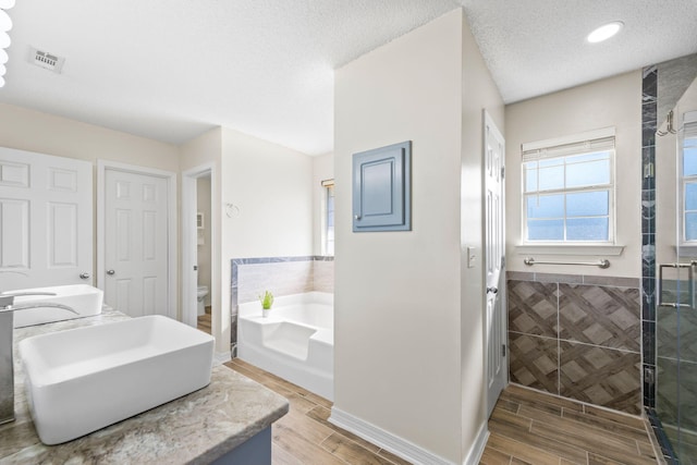 full bathroom with a textured ceiling, sink, wood-type flooring, tile walls, and toilet