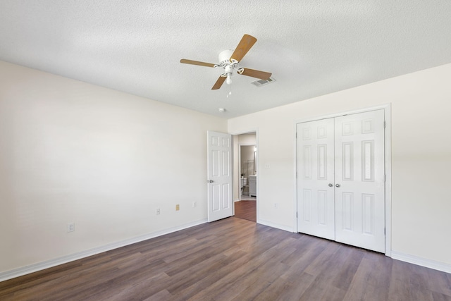 unfurnished bedroom featuring ceiling fan, a closet, dark wood-type flooring, and a textured ceiling