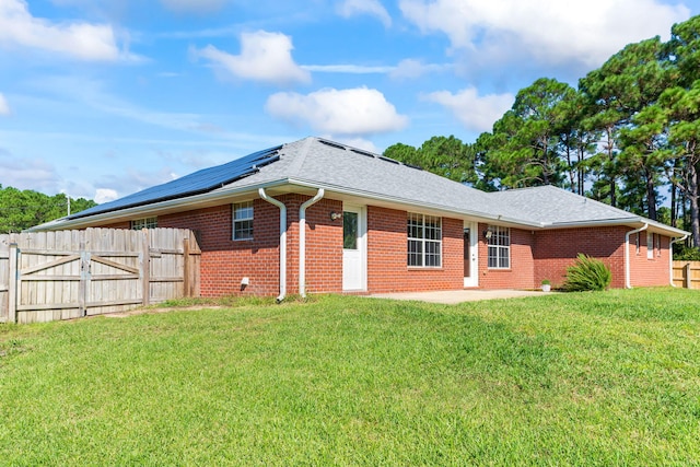 rear view of property featuring solar panels, a yard, and a patio