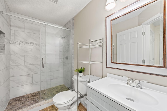 bathroom with hardwood / wood-style floors, a textured ceiling, toilet, a shower with door, and vanity