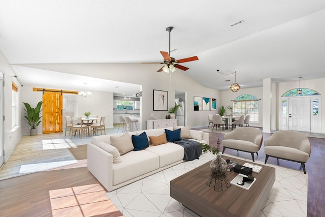 living room with light hardwood / wood-style floors, a barn door, a healthy amount of sunlight, and vaulted ceiling