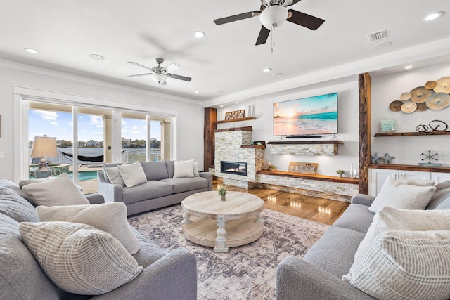 living room featuring ceiling fan, wood-type flooring, and a fireplace