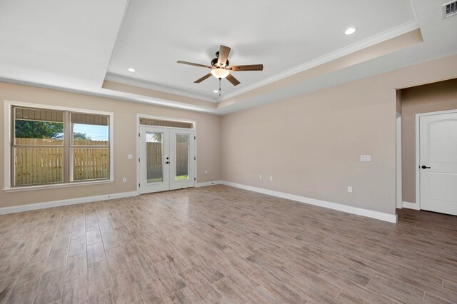 interior space with a tray ceiling, ceiling fan, wood-type flooring, and ornamental molding