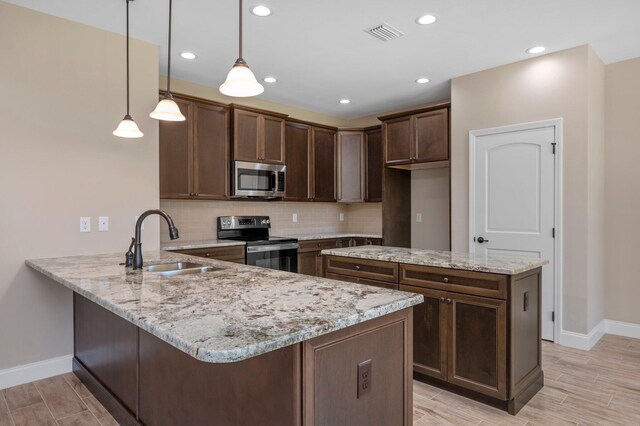 kitchen with pendant lighting, kitchen peninsula, sink, stainless steel appliances, and light wood-type flooring