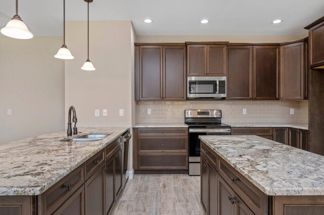 kitchen featuring pendant lighting, tasteful backsplash, a kitchen island, light stone countertops, and appliances with stainless steel finishes