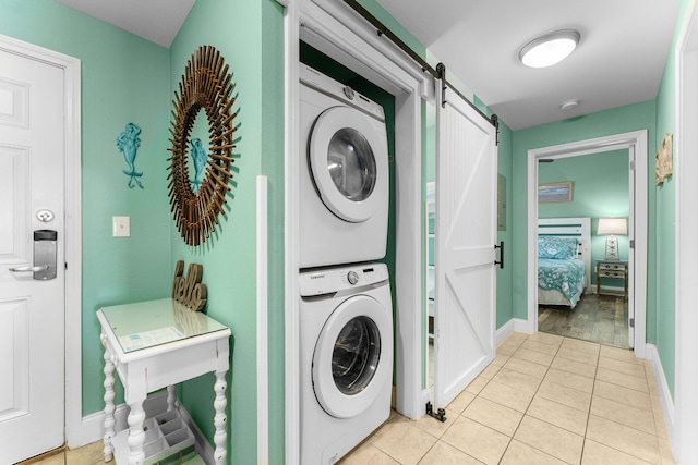 clothes washing area with a barn door, light hardwood / wood-style floors, and stacked washer / drying machine