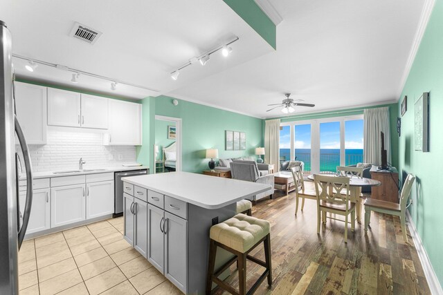 kitchen with light hardwood / wood-style floors, a center island, white cabinetry, ceiling fan, and a water view