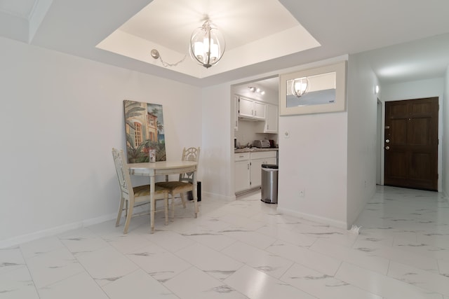 unfurnished dining area with a notable chandelier and a tray ceiling