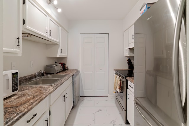 kitchen with appliances with stainless steel finishes, dark stone countertops, white cabinetry, and sink