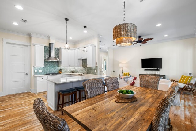 dining room with light hardwood / wood-style flooring, ceiling fan, ornamental molding, and sink