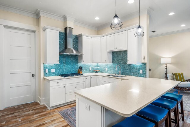 kitchen featuring wall chimney exhaust hood, light wood-type flooring, white cabinetry, and sink