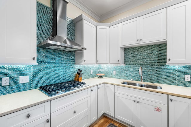 kitchen with decorative backsplash, white cabinets, wall chimney exhaust hood, ornamental molding, and sink