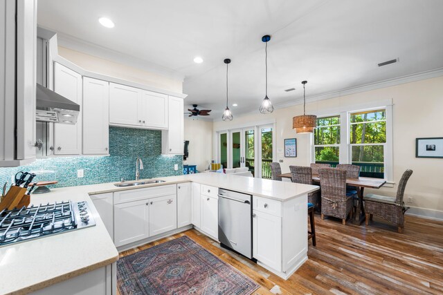 kitchen with white cabinets, kitchen peninsula, decorative light fixtures, dark wood-type flooring, and appliances with stainless steel finishes