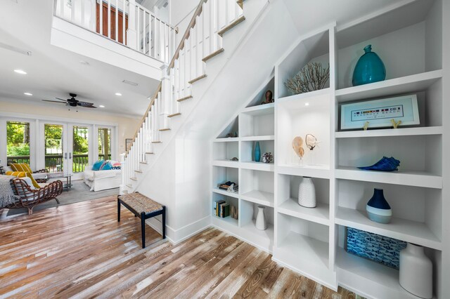 interior space featuring built in shelves, ceiling fan, french doors, hardwood / wood-style flooring, and crown molding