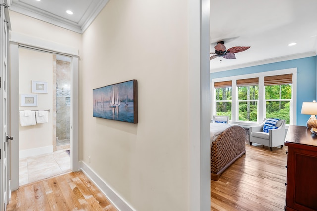 hallway with ornamental molding and light hardwood / wood-style flooring