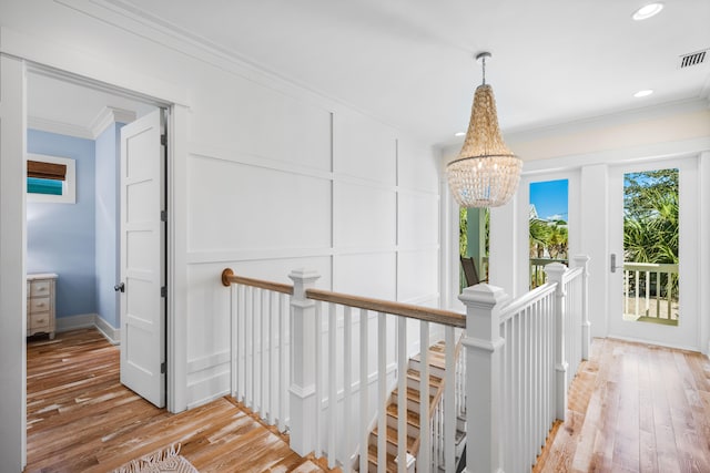 corridor featuring light hardwood / wood-style floors, ornamental molding, and a chandelier