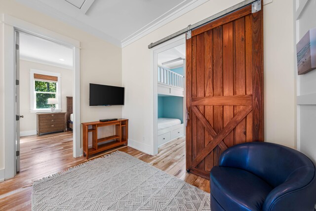 living area featuring ornamental molding, light hardwood / wood-style flooring, and a barn door