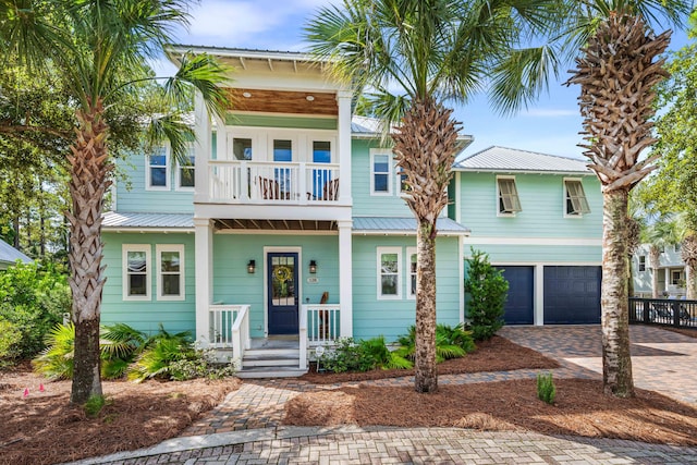 beach home featuring a balcony, covered porch, and a garage