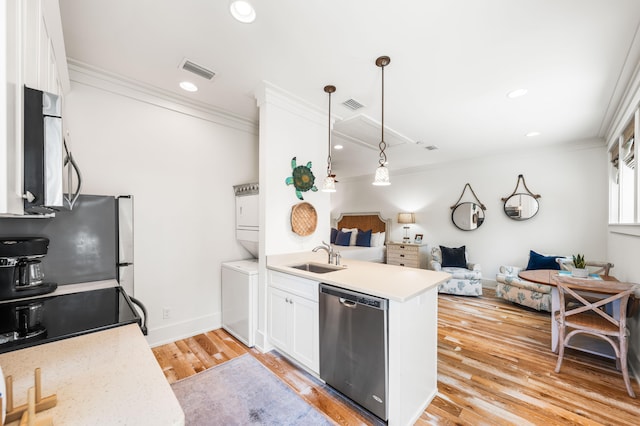 kitchen with hanging light fixtures, white cabinets, stainless steel appliances, light wood-type flooring, and stacked washer and dryer