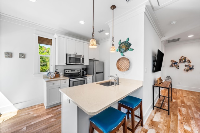 kitchen with sink, white cabinetry, kitchen peninsula, a kitchen breakfast bar, and stainless steel appliances