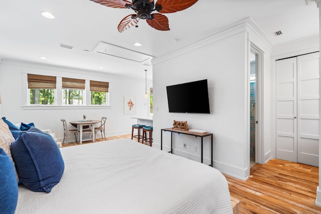 bedroom featuring ceiling fan, light wood-type flooring, crown molding, and a closet