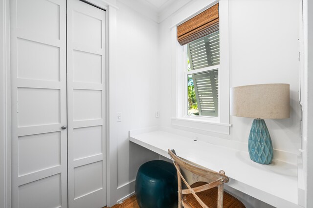 office area with built in desk, wood-type flooring, and ornamental molding