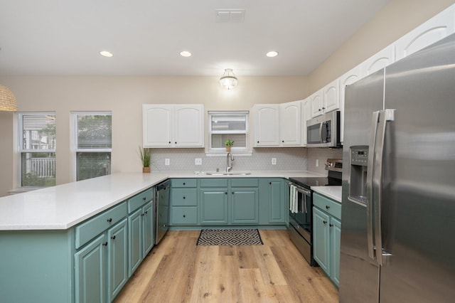 kitchen featuring white cabinets, kitchen peninsula, stainless steel appliances, light wood-type flooring, and sink